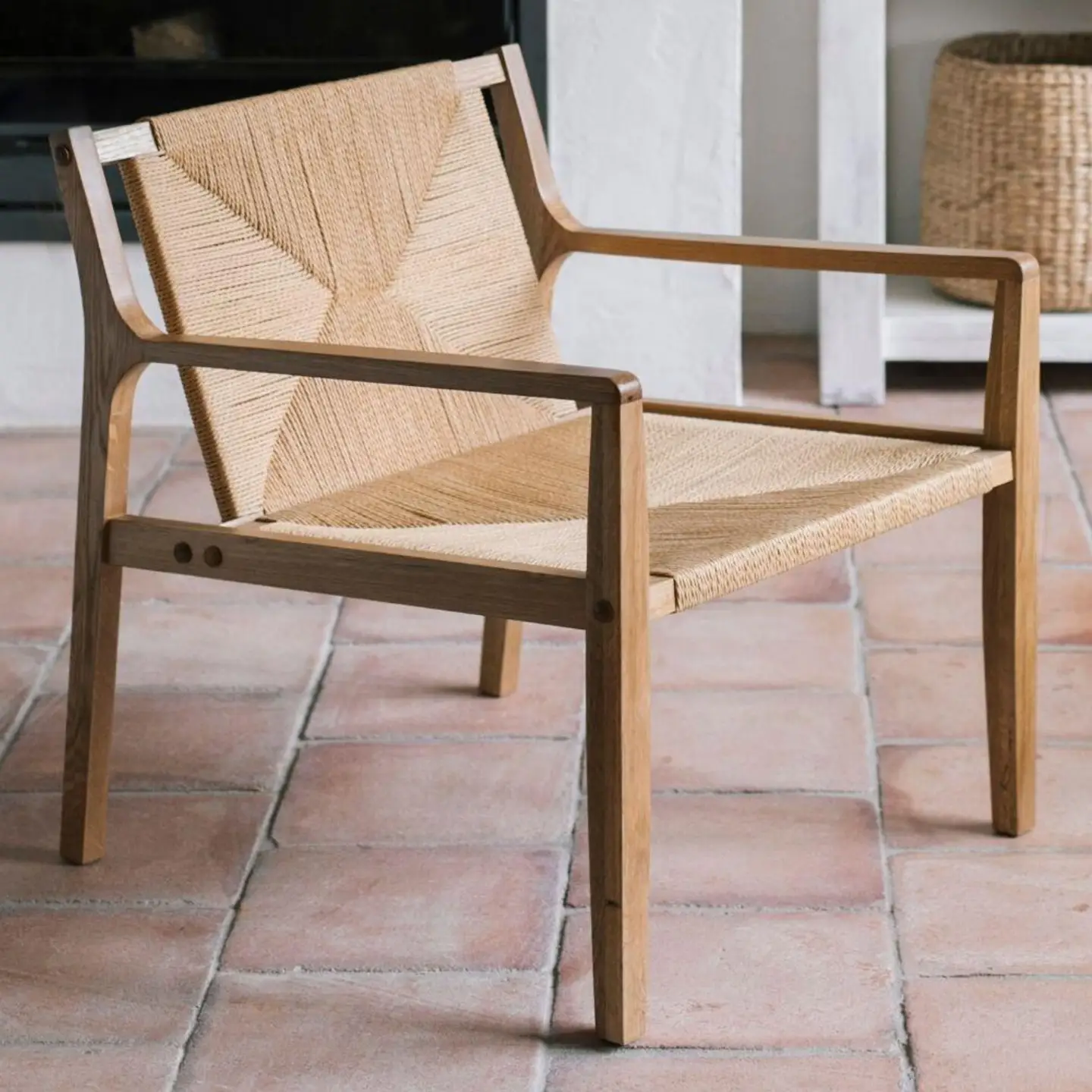 Loungefåtölj i trä med flätad sits och rygg på terrakottafärgat golv
